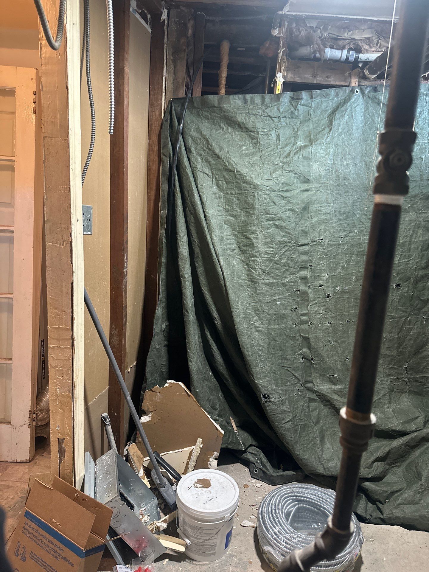 Wall opened with tarp containment and debris