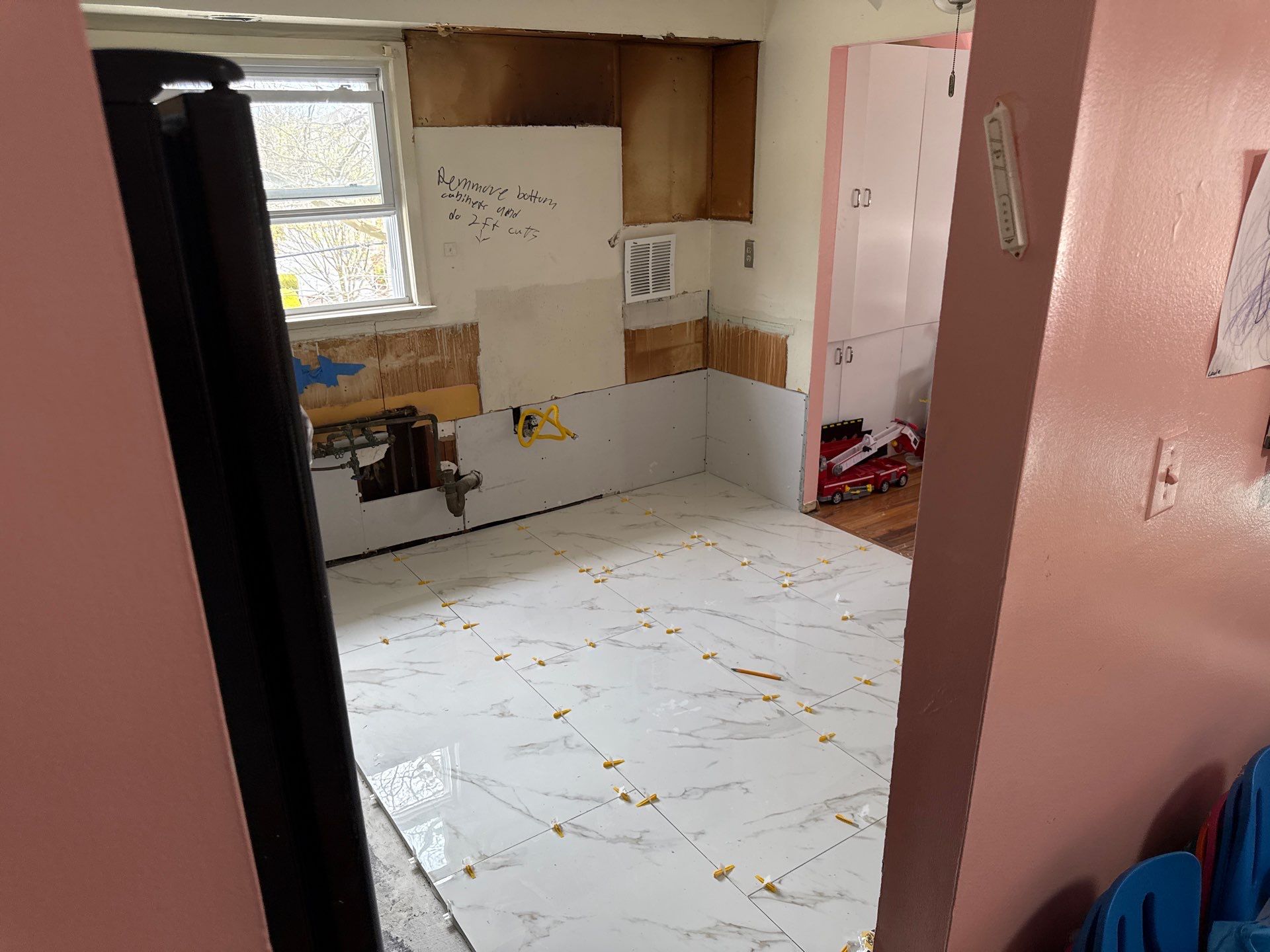 New marble-look porcelain tile being laid with leveling clips